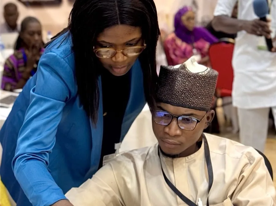 A facilitator working through an exercise at a laptop with a participant during a training session.