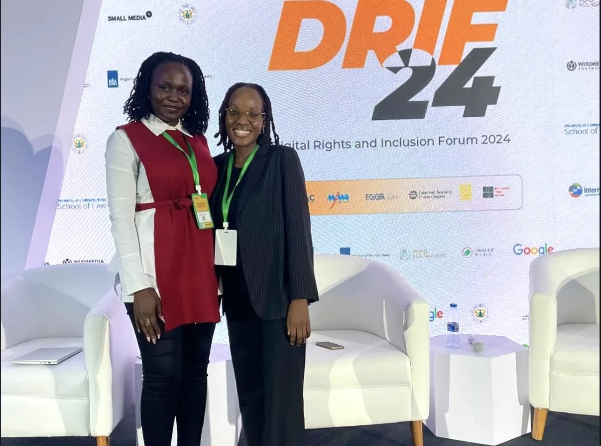 Two Resilience Technologies delegates at DRIF24, standing together in front of the forum banner.